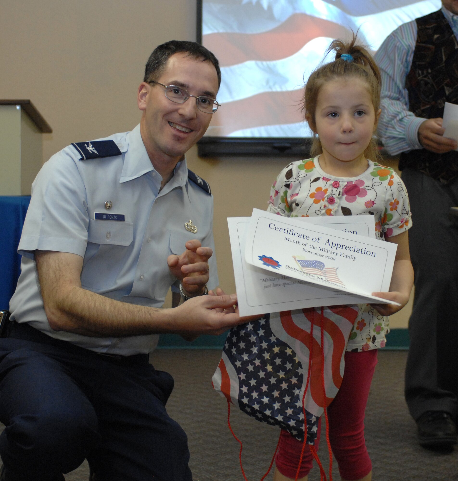 Col. Stephen DiFonzo, 49th Mission Support Group commander, presents an award to Makenzie Sylvester for winning 1st place in the 6 and under category of the essay contest at the Airman and Family Readiness Center at Holloman Air Force Base, N.M., Nov. 24. The theme for the essay contest was 'My Military Hero" in support of Military Family Appreciation Month. (U.S. Air Force photo/Airman Sondra M. Escutia)