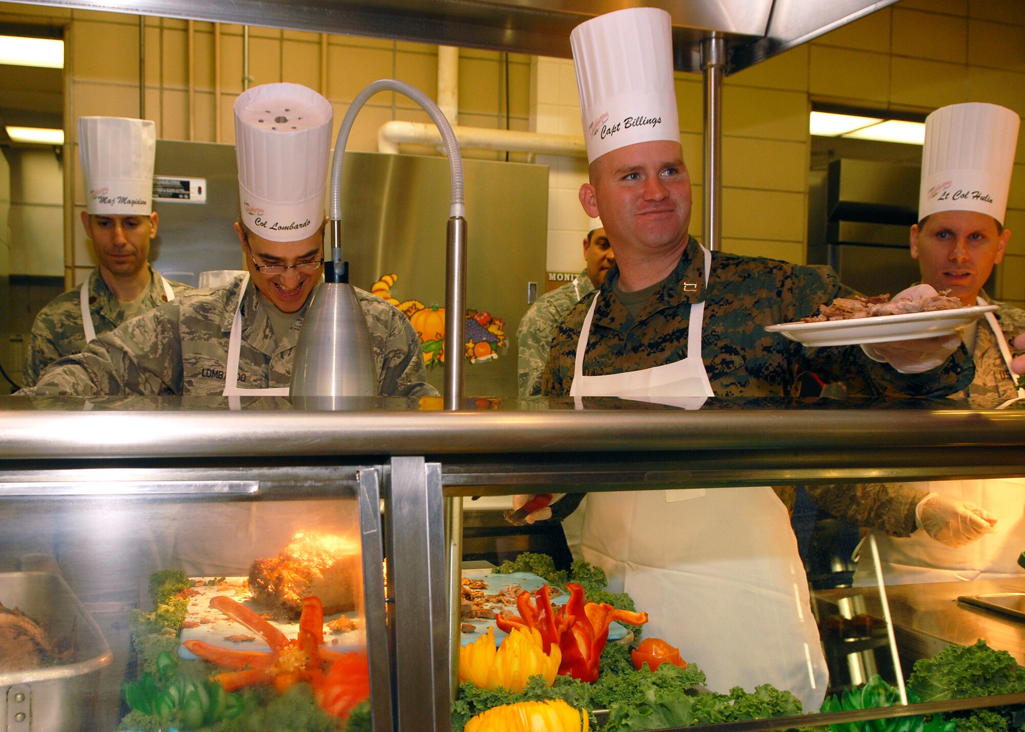 Captain Henry Billings (right), Goodfellow Marine Corps Detachment commanding officer, and Colonel Anthony Lombardo, 17th Training Group commander, and other wing leaders serve a traditional Thanksgiving meal to Goodfellow Air Force Base personnel at the Western Winds Dining Facility on Nov. 27.  Each Thanksgiving leadership from the various units on base assists with serving the meal to dorm residents and others who remain on base during the holiday.  (U.S. Air Force photo by Senior Airman Kasabyan Musal).