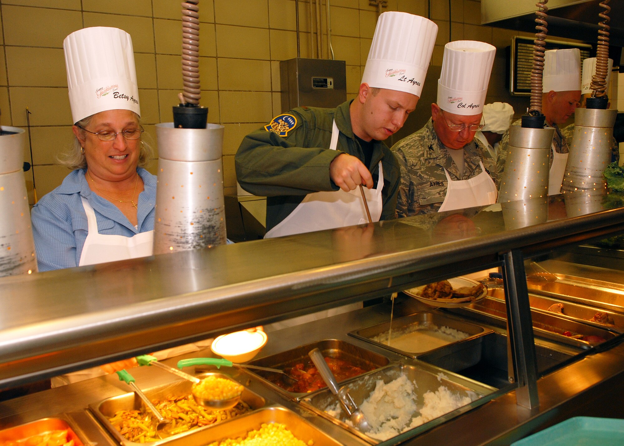 Betsy Ayres (left), 2nd Lieutenant Stephen Ayres, 47th Operations Support Squadron, and Colonel Richard Ayres, 17th Training Wing commander, serve a traditional Thanksgiving meal to Goodfellow Air Force Base personnel at the Western Winds Dining Facility on Nov. 27.  Each Thanksgiving leadership from the various units on base assists with serving the meal to dorm residents and others who remain on base during the holiday.  (U.S. Air Force photo by Senior Airman Kasabyan Musal).