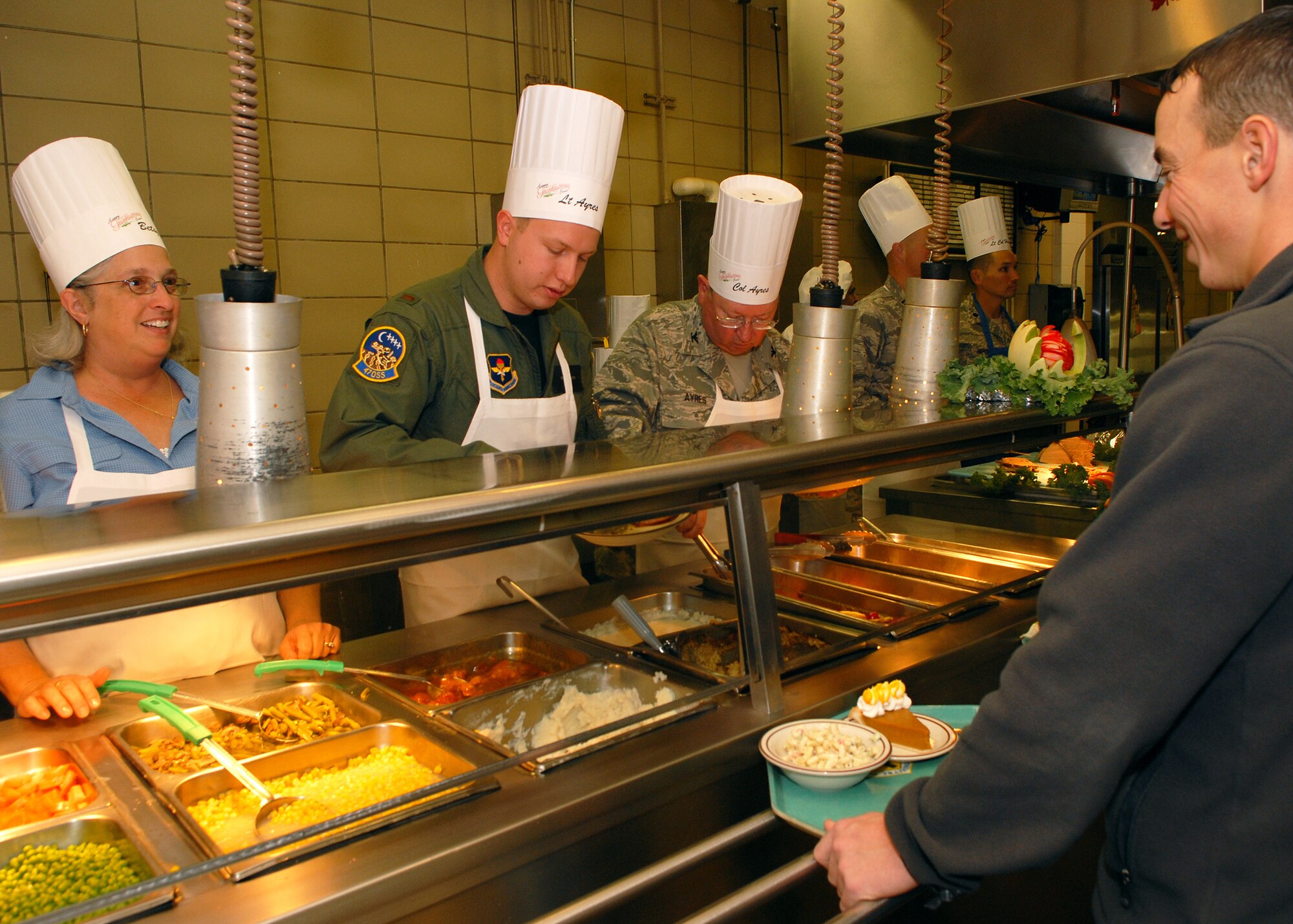Betsy Ayres (left), 2nd Lieutenant Stephen Ayres, 47th Operations Support Squadron, and Colonel Richard Ayres, 17th Training Wing commander, serve a traditional Thanksgiving meal to Goodfellow Air Force Base personnel at the Western Winds Dining Facility on Nov. 27.  Each Thanksgiving leadership from the various units on base assists with serving the meal to dorm residents and others who remain on base during the holiday.  (U.S. Air Force photo by Senior Airman Kasabyan Musal).