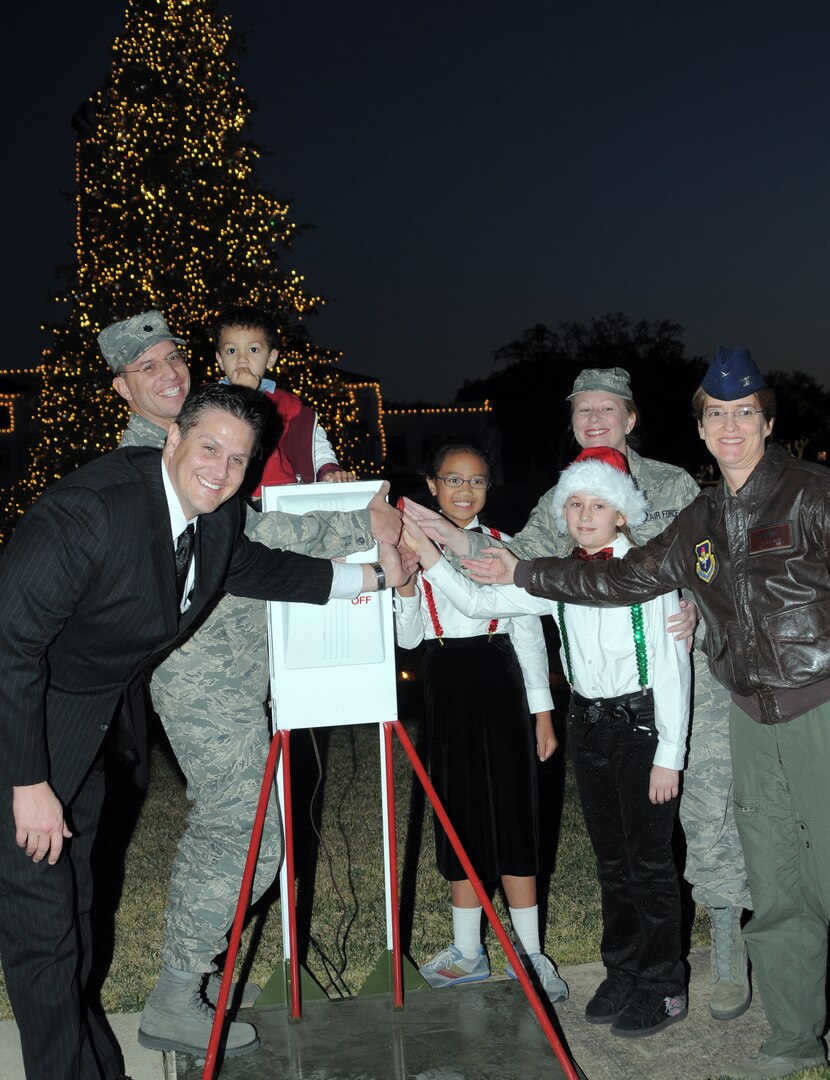 Col. Jacqueline Van Ovost (right), 12th Flying Training Wing commander, (U.S. Air Force photo by Melissa Peterson), McKenna Cunningham (with Santa cap), daughter of Gregory (front left) and Tech. Sgt. Laurie Cunningham (standing in back), Sarai Bringhurst (center), daughter of Lt. Col. David Bringhurst (back left) flip the switch on the holiday tree during a lighting ceremony in Washington Circle on Dec. 2. (U.S. Air Force photo by Melissa Peterson)