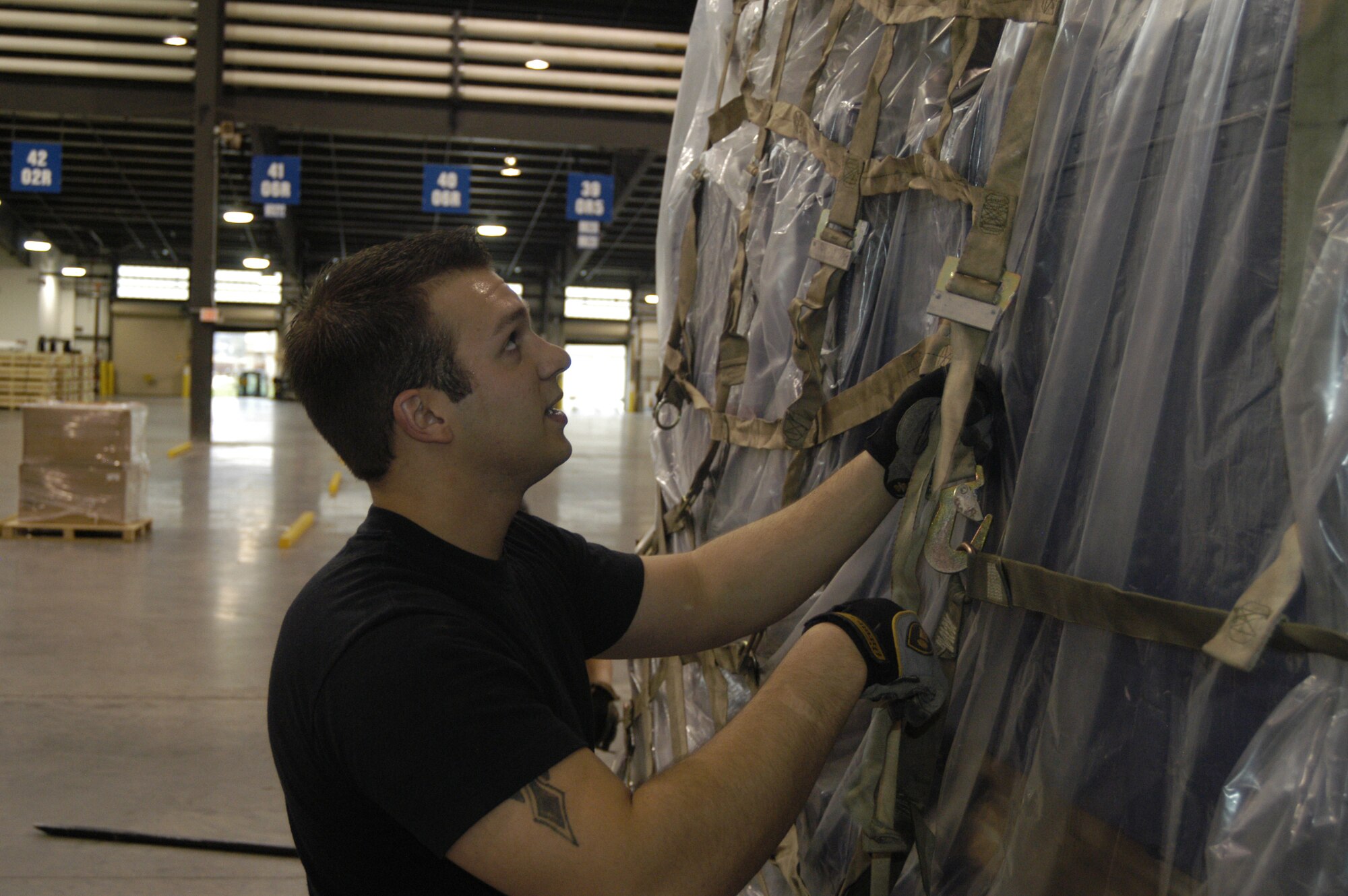 Airman 1st Class Roland Lester, 436th Aerial Port Squadron cargo processor, hooks a cargo net on a pallet filled with equipment from World Wrestling Entertainment Nov. 30 Porters created several pallets of equipment which accompanied several WWE superstars to Baghdad, Iraq, aboard a Dover C-17. The World Wrestling Entertainment flew to Iraq to put on morale shows for deployed servicemembers. (U.S. Air Force photo/Senior Airman James Bolinger)