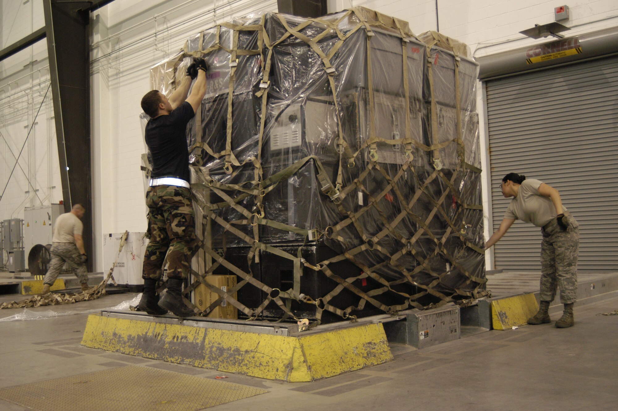 Airman 1st Class Corey Watson and Airman Sara Rocero-Barrett, 436th Aerial Port Squadron cargo processors, hook a cargo net on a pallet filled with equipment from World Wrestling Entertainment Nov. 30. Porters created several pallets of equipment which accompanied several WWE superstars to Baghdad, Iraq, aboard a Dover C-17. The World Wrestling Entertainment flew to Iraq to put on morale shows for deployed servicemembers. (U.S. Air Force photo/Senior Airman James Bolinger)