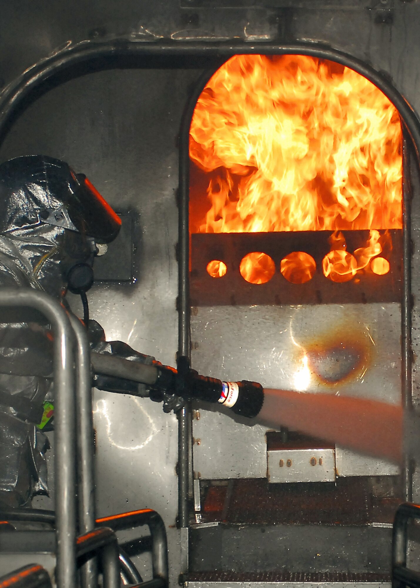 Firefighters from the 386th Expeditionary Civil Engineer Squadron extinguish a fire on an aircraft fire trainer Nov. 24 at an air base in Southwest Asia. The firefighters must complete one daytime and nighttime live fire burn annually. (U.S. Air Force photo/Capt. Suzanne VanderWeyst) 
