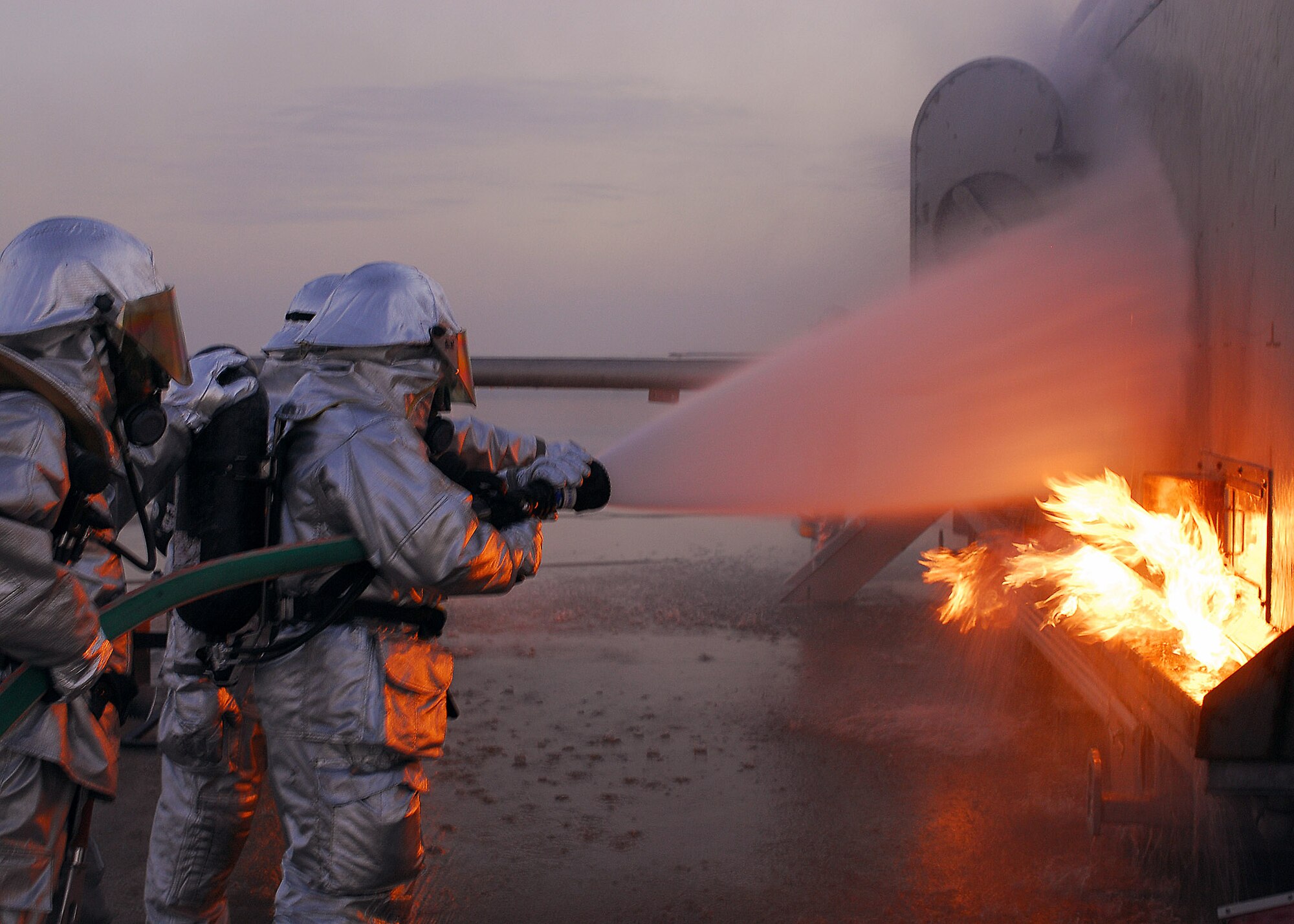 Firefighters from the 386th Expeditionary Civil Engineer Squadron extinguish a fire on an aircraft fire trainer Nov. 24 at an air base in Southwest Asia. The firefighters must complete one daytime and nighttime live fire burn annually. (U.S. Air Force photo/Capt. Suzanne VanderWeyst) 
