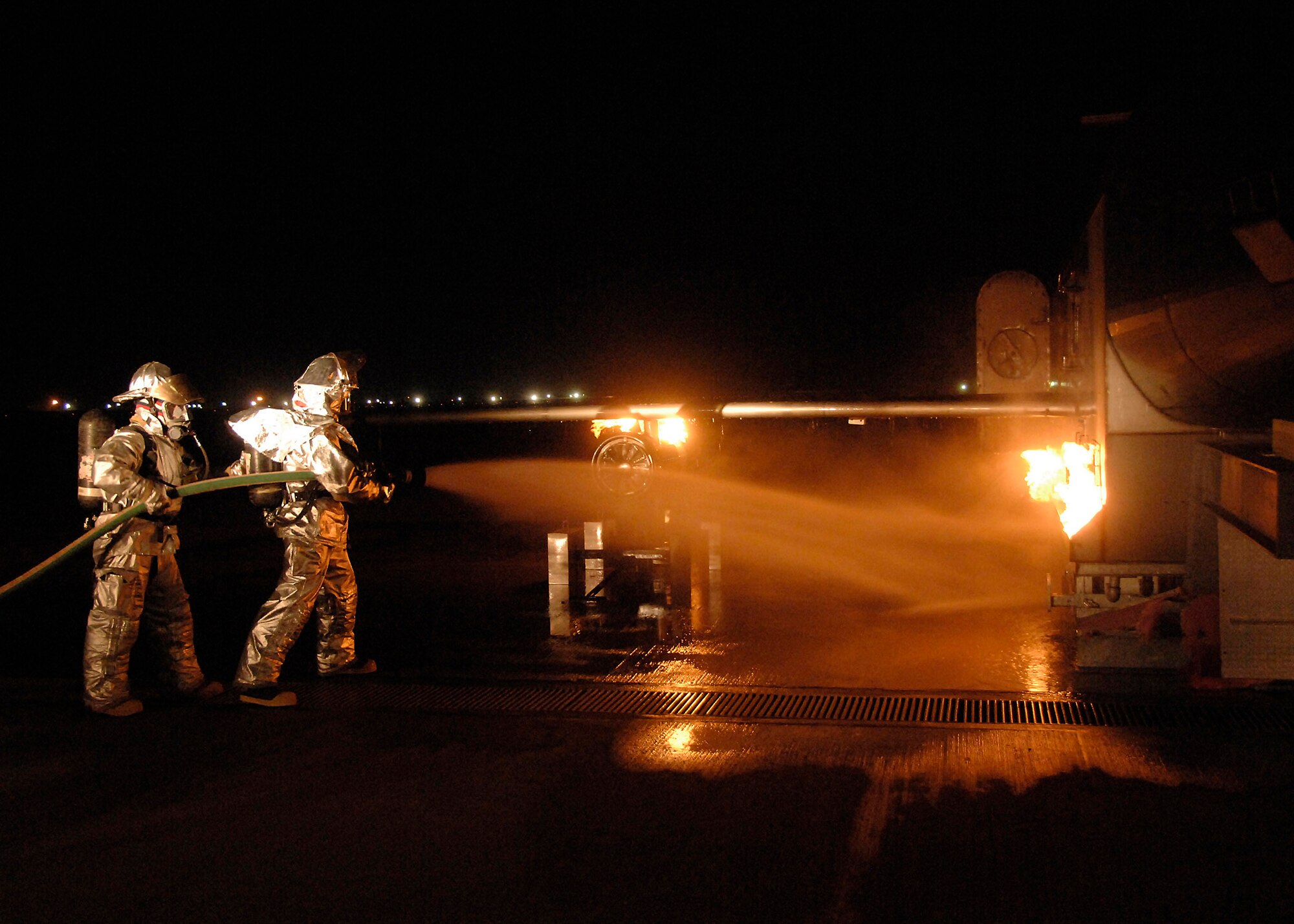 Firefighters from the 386th Expeditionary Civil Engineer Squadron extinguish a fire on an aircraft fire trainer Nov. 24 at an air base in Southwest Asia. The firefighters must complete one daytime and nighttime live fire burn annually. (U.S. Air Force photo/Capt. Suzanne VanderWeyst) 
