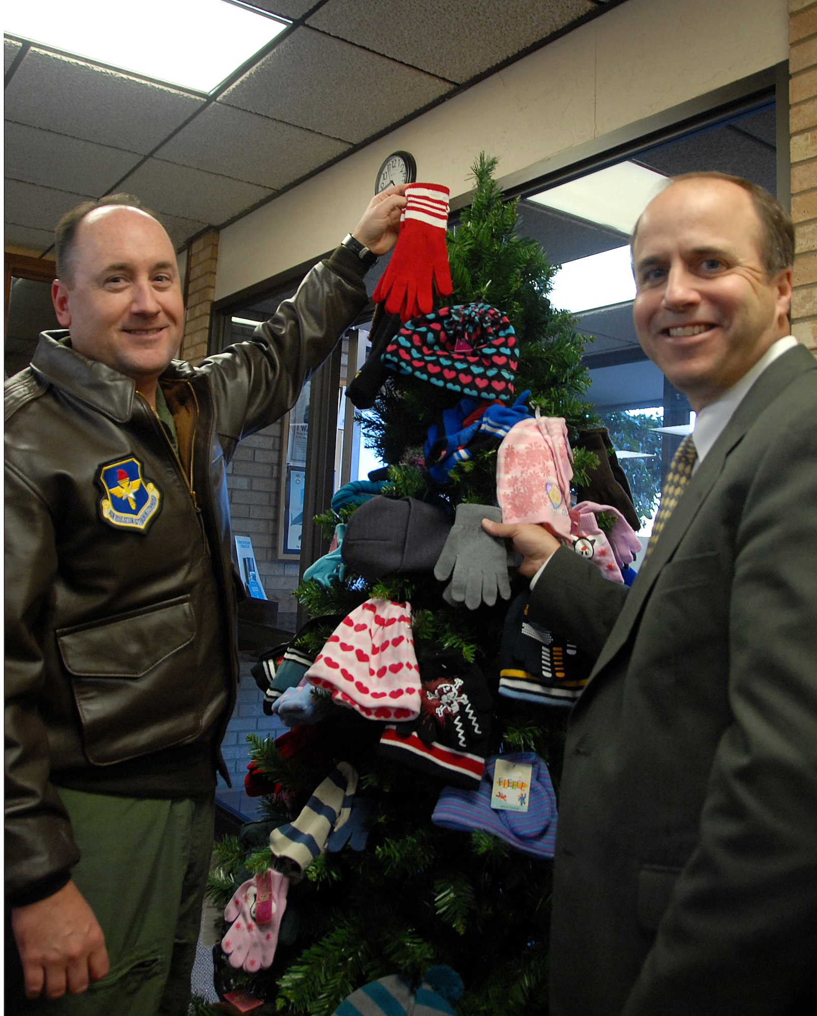 Col. Stuart Shaw, 97th Air Mobility Wing vice commander and Jeff Greenlee, President of NBC Bank in Altus, Okla., pin mittens on the Altus AFB branch of NBC’s  annual mitten trees 20 Nov. 2008. All the donated mittens hung on the trees will be given to area support agencies that will redistribute them to local children in need of warm winter clothing. (U.S. Air Force photo/Airman 1st Class Cherice Bryant)
