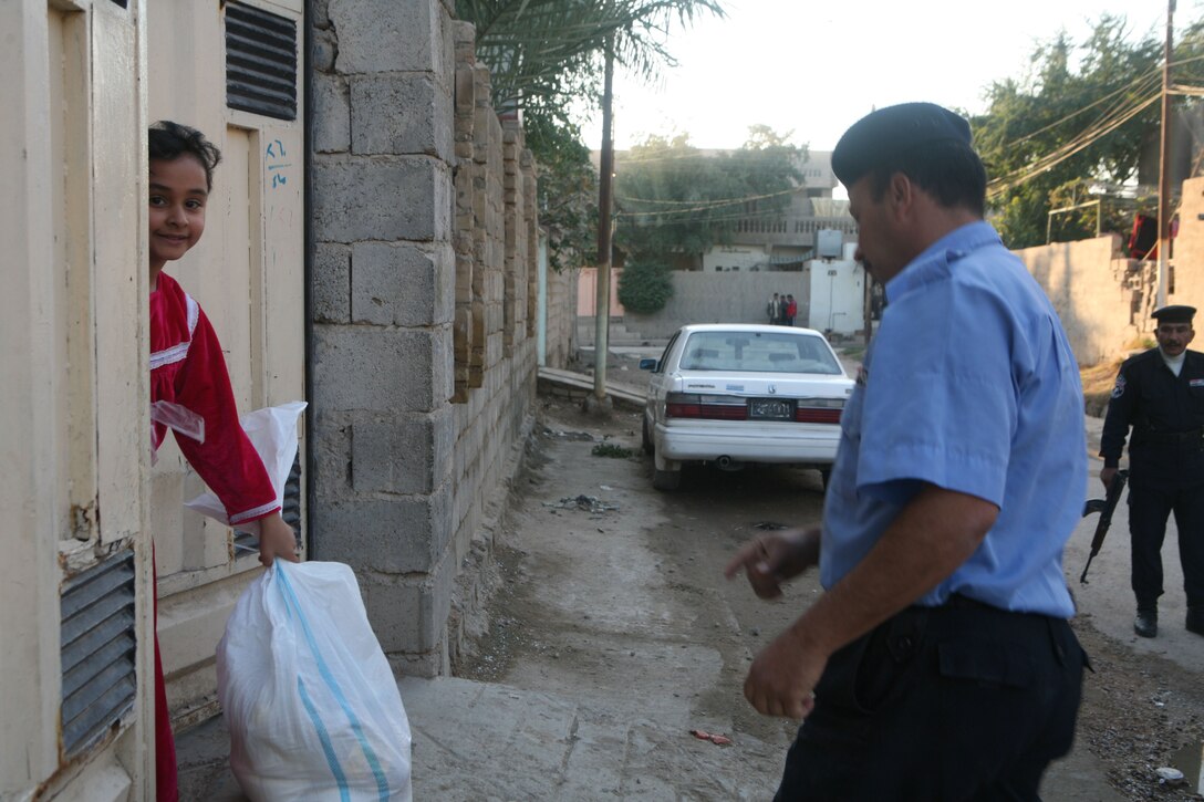 Iraqi Police from the Muallimeen IP Station pass out food bags during a humanitarian-aid operation in Fallujah, Iraq, Dec. 3. (Official Marine Corps photo by Cpl. Chris T. Mann)::r::::n::(Released)::r::::n::