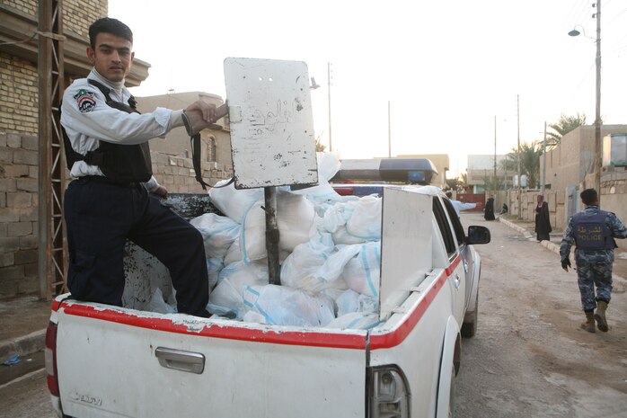 Iraqi Police from the Muallimeen IP Station pass out food bags during a humanitarian-aid operation in Fallujah, Iraq, Dec. 3. (Official Marine Corps photo by Cpl. Chris T. Mann)::r::::n::(Released)::r::::n::