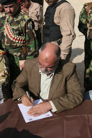 Hassan Yahyah Hassan, who is a representative for the ministry of electricity as well as the overall director of the Haditha Dam, signs the last bit of paperwork to officially turn the structure over from the Coalition forces to the Government of Iraq Dec 3. The dam security is being taken over by Iraqi Army and police. The Haditha Dam provides approximately one-third of Iraq's electricity. ::r::::n::