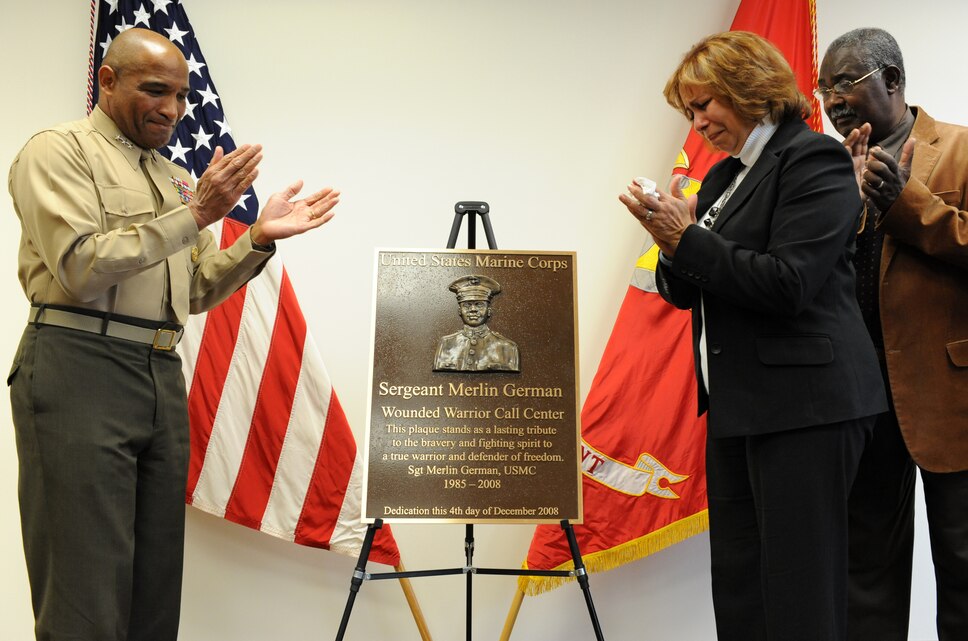 Lt. Gen. Ronald S. Coleman, deputy commandant of Manpower and Reserve Affairs, and family members of Sgt. Merlin German, a Marine who died from injuries sustained in Iraq, applaud after unveiling a plaque during the Sergeant Merlin German Wounded Warrior Regiment Call Center dedication ceremony Dec. 4.