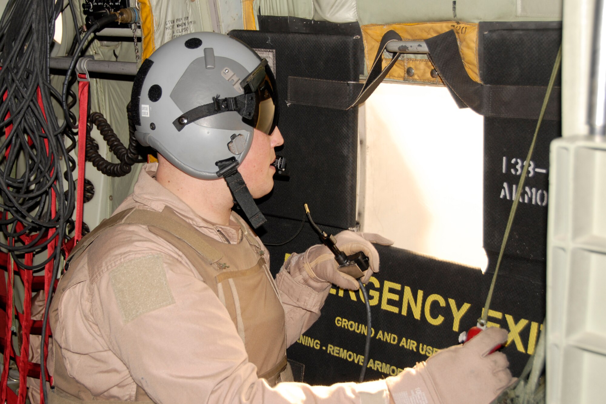 Tech. Sgt. Jason Weber, Loadmaster with the 109th Airlift Squadron, 133rd Airlift Wing, peers out the rear of the C-130 Hercules aircraft while flying to Herat, Afghanistan to keep watch for any threats and is prepared to release flares if needed Monday, Dec. 1, 2008. 