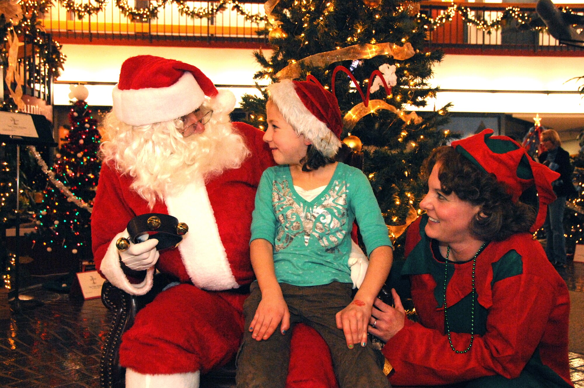Sophia Knack, 6,  tells Santa what she wants for Christmas, while Santa?s helper Diane Soave looks on at the Seventh Annual Travis Fischer House Tree Festival and Auction Dec. 3. The silent auction event raises money for the Travis Fischer House, who provides billeting for military families free of charge while their loved one receives care at the David Grant Medical Center here. (U.S. Air Force photo/Nan Wylie)