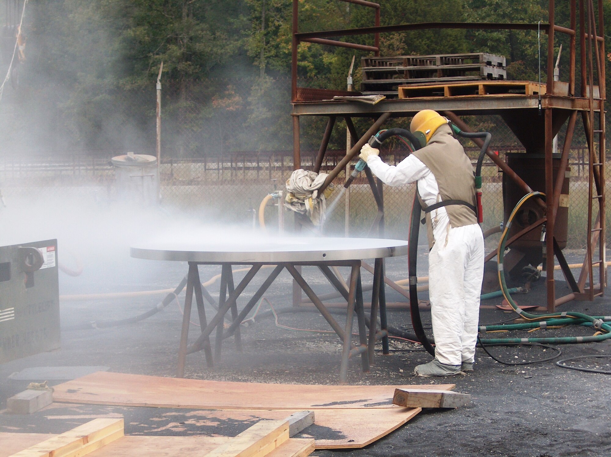 Carlton Hobbs, ATA craftsman, is polishing a 4,000 pound weight using bicarbonate of soda as the blasting medium. The weight is part of a force calibration machine that was refurbished at AEDC for installation at the Army Primary Standards Lab at Redstone Arsenal at Huntsville, AL. (Photo by James Winchester)