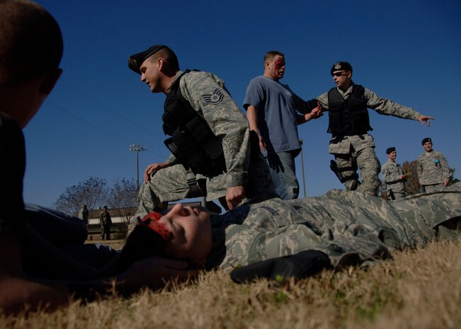 Members from the 437th Security Forces Squadron secure the area while performing on-scene self-aid buddy care behind the Fitness and Sports Center Dec. 2. The base conducted the exercise to test how Airmen respond to a simulated explosion caused by an improvised explosive device. (U.S. Air Force photo/Senior Airman Timothy Taylor)