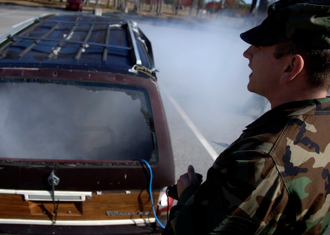Tech. Sgt. Stephen Thompson operates a smoke machine inside the vehicle to simulate an explosion behind the Fitness and Sports Center Dec. 2. The base conducted the exercise to test how Airmen respond to a simulated explosion caused by an improvised explosive device. Sergeant Thompson is with the 437th Civil Engineer Squadron. (U.S. Air Force photo/Senior Airman Timothy Taylor) 
