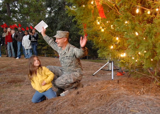 Col. John "Red" Millander and Jenesis Rodriguez light the holiday tree on Charleston AFB Dec. 3. The annual holiday tree lighting ceremony included announcements of the greeting card winners, children singing and the arrival of Santa Claus on a firetruck. Colonel Millander is the 437th Airlift Wing commander and Jenesis is the daughter of David and Staff Sgt. Amber Rodriguez. (U.S. Air Force photo/Airman 1st Class Katie Gieratz)
