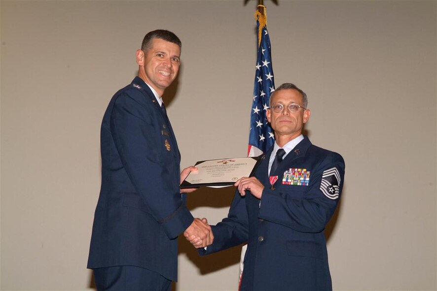 Col. Jose A. Rivera (left), 5th Combat Communications Group commander, presents the Bronze Star citation to Chief Master Sgt. Thomas Perry, a member of the 53rd Combat Communications Squadron. U.S. Air Force photo by Tommie Horton