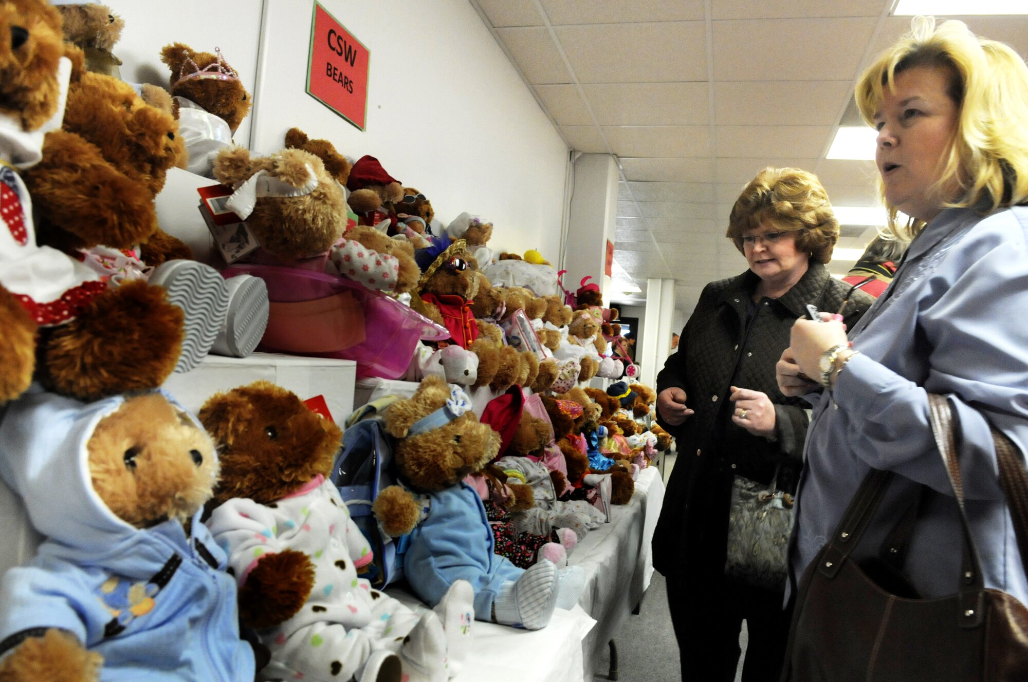 Donna Walcott and Cathy Schoonover, 560th ACSG, look over some bears that were dressed for WRALC Contracting's annual Christmas Project of dressing bears and filling stockings for the Salvation Army. The Salvation Army provides teddy bears and Christmas stockings, and the “Contracting Family” fills the stockings and creates unique bear personalities for many area children on Christmas morning. This year 250 bears and 200 stockings were donated. U. S. Air Force photo by Sue Sapp
