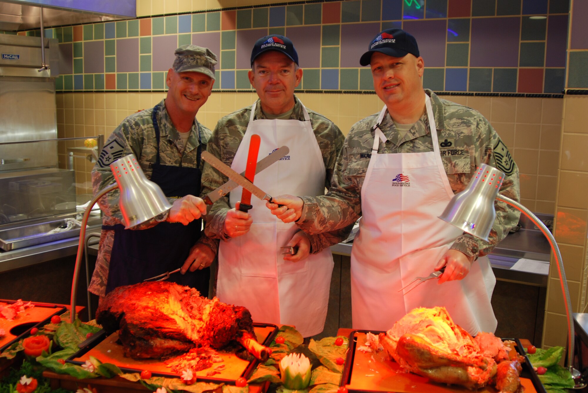 MCCONNELL AIR FORCE BASE, Kan. -- The three musketeers of meat carving, Master Sgt. Daniel Bryant. 22nd Security Forces Squadron first sergeant, Colonel Alan Reid, 22nd Medical Group commander, and Master Sergeant Brian Ward, 22nd Logistics Readiness Squadron first sergeant, serve turkey, ham, and roast beef during a Thanksgiving feast for McConnell members, served by wing leadership, Nov. 27 at the base dining facility. (Photo by Airman 1st Class Jessica Lockoski)