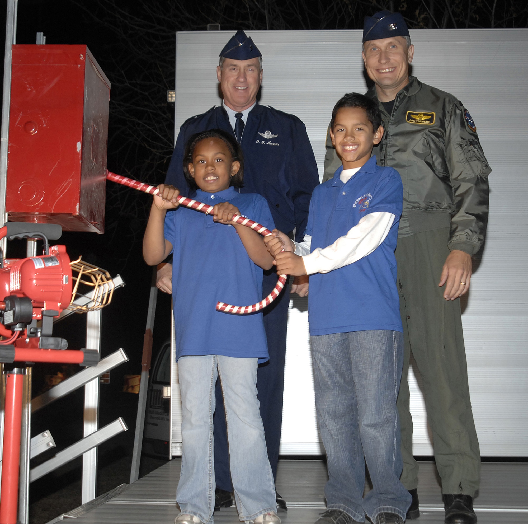Sheppard Elementary students Eendya Layton, left, and Kenyon Tabor throw the switch Dec. 2 to light up the holiday tree near Sheppard's Commissary. Brig. Gen. O.G. Mannon, 82nd Training Wing commander, and Col. Daniel Torweihe, 80th Flying Training Wing vice commander, were on hand to help usher in the holiday season. (U.S. Air Force photo/Lou Anne Sledge)