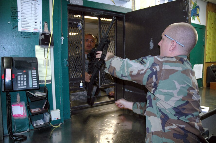 Tech. Sgt. David Moore, 341st Security Support Squadron armory NCO in charge, hands an M-4 carbine to Senior Ariman Ryan Morse, 341st SSPTS armorer, while demonstrating a weapons return Nov. 25. (U.S Air Force photo/Senior Airman Dillon White) 
