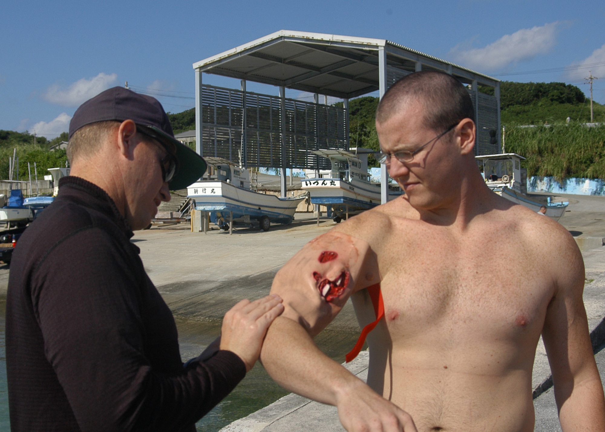 KADENA AIR BASE, Japan -- Maj. (Dr.) Nathan Cecava, a flight surgeon with the 353rd Operations Support Squadron, attaches a simulated open fracture to Airman 1st Class Kevin Christensen, a 353rd OSS aircrew flight equipment specialist, during a training exercise here Dec. 2. Airman Christensen played one of four survivors of a simulated aircraft accident. Pararescuemen and combat controllers from the 320th STS jumped from a MC-130H Combat Talon II to search for, and recover, the survivors. The event was part of a 353rd Special Operations Group training exercise testing the group?s ability to conduct search and rescue operations from start to finish. (U.S. Air Force photo by Tech. Sgt. Aaron Cram)                              