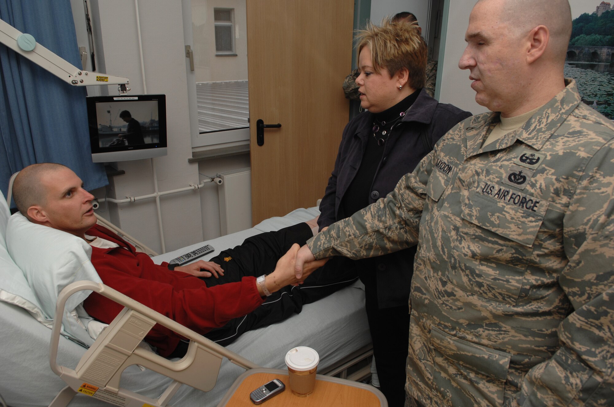 Canadian Army Corporal Robbie Stephenson (left), injured by an improvised explosive device blast during a convoy while deployed in Afghanistan, is visited by Staff Sgt. Matthew Slaydon and his wife, Annette, Landstuhl Regional Medical Center, Germany, Nov. 21, 2008. Sgt. Slaydon was severely injured in Iraq 13 months ago during a deployment there as an explosive ordinance disposal technician and is visiting LRMC as part of a morale tour, following his recovery. (U.S. Air Force photo by Airman 1st Class Tony R. Ritter)