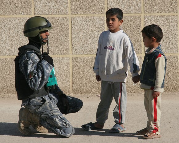 An Iraqi Police Officer talks to children as in Ramadi, Iraq Dec. 4. Marines and IPs patrol to protect people in the area and to provide an opportunity for the IPs to practice techniques the Marines have taught them.
