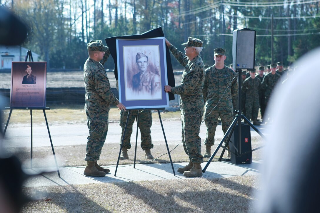 Sgt. Dany R. Gray, a combat illustrator, and Navy Capt. Efren Saenz, the commanding officer of Field Medical Training school, unveil a portrait of Petty Officer 2nd Class John H. Bradley, Dec. 4 during a ground breaking ceremony on Camp Johnson, one of the Marine Corps bases Camp Lejeune. Bradley was legendary for being pictured in the famous flag-raising of Mount Suribachi, one of the bloodiest Marine casualty producing battles in Marine Corps history. The new FMTS building will be dedicated after Bradley in honor of his devoted service as a corpsman.
