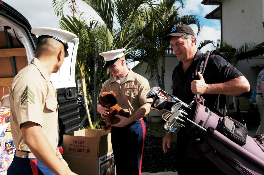 Jack Flanagan, Navy League member, hands off a toy to Cpl. Mark Barone and Sgt. Leo Cruz, both from 4th Force Reconnaissance Company, as he prepares to take part in the Navy League's 3rd Annual Toys for Tots Golf Tournament Dec. 5. All of the proceeds from the event benefit the Marine Corps Reserve's annual Toys for Tots campaign. The Navy League received an estimated 400 toys at the event.