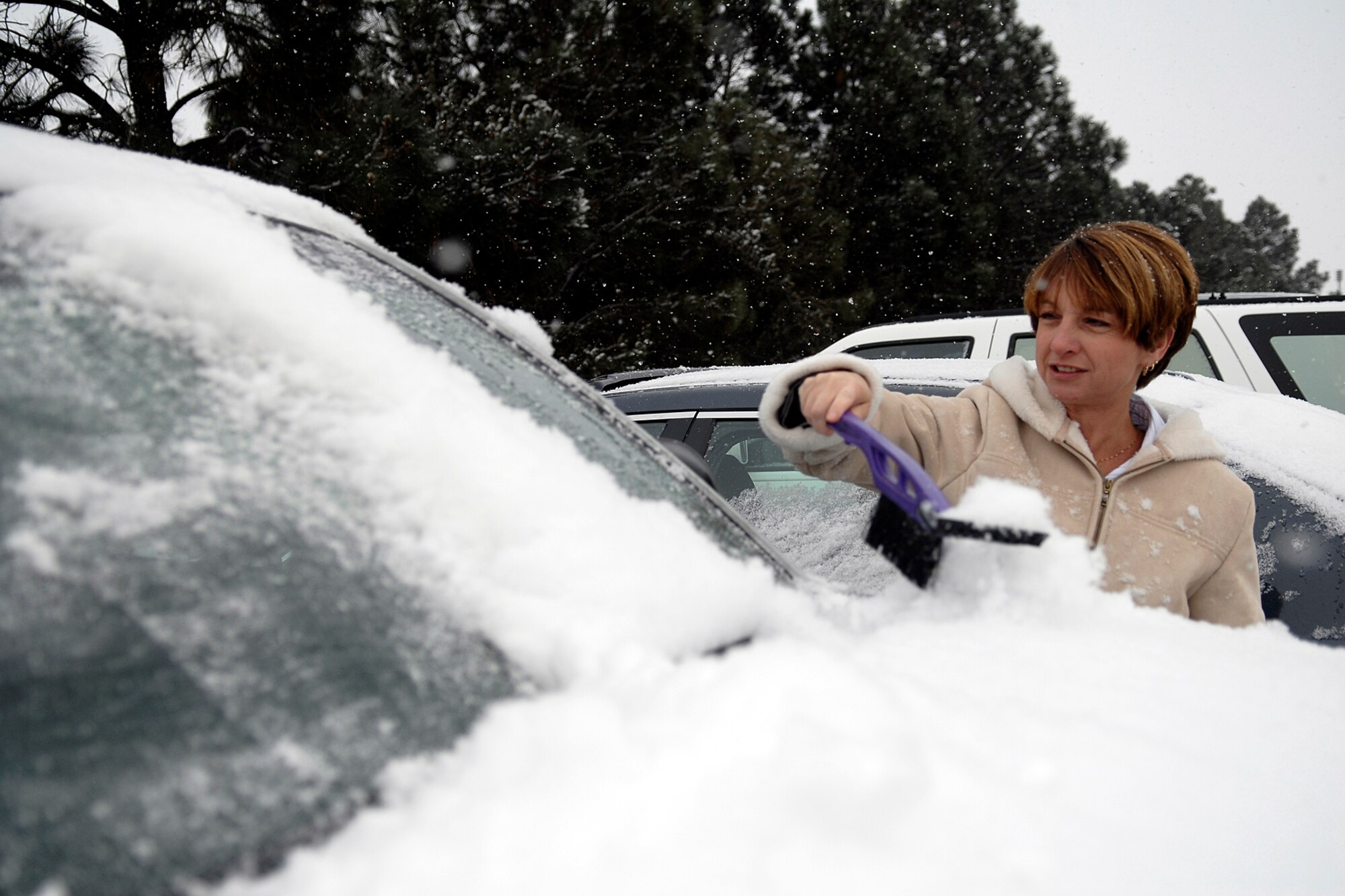 Ms. Linda Cook of 21 CPTS/FMA cleans the snow off her car in preparation for her drive home after early release was announced Dec 4th. (Photo by Rob Bussard)
