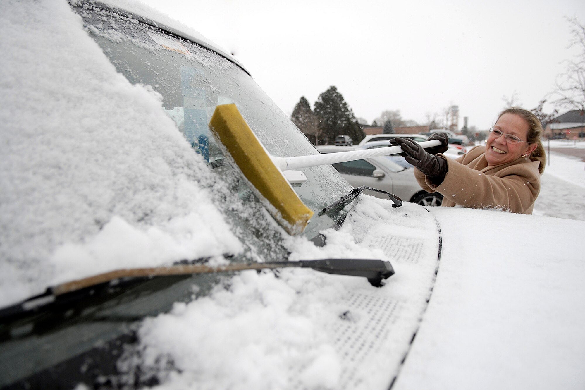 Ms. Bobette Groce of 21 FSS/Base training cleans the snow off her Ford Bronco in preparation for her drive home after early release was announced Dec 4th. (Photo by Rob Bussard)