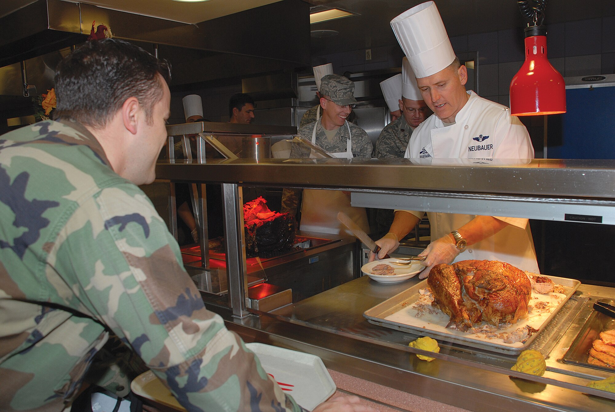 Airman Brandon Bright, 56th Maintenance Operations Squadron, looks on as Brig. Gen. Kurt Neubauer, 56th Fighter Wing commander, carves a Thanksgiving Day turkey for Luke Airmen at the Ray V. Hensman Dining Facility Nov. 27. (photo by Airmen 1st Clas Tracie Forte)