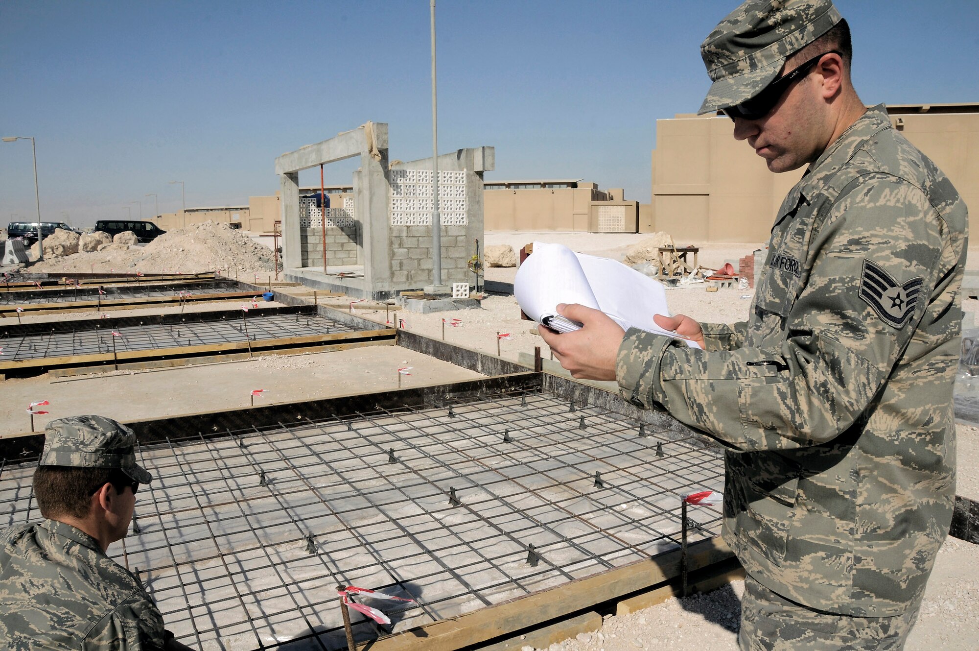 Staff Sgt. Ryan Burk verifies a specification of a contracting job while Staff Sgt. Doug Keeler reviews the specifications and drawings of a new bus stop Dec. 4 at an air base in Southwest Asia. Both are contracting officers assigned to the 379th Expeditionary Contracting Squadron. Sergeant Burk, a native of Fuquay-Varina, N.C., is deployed from Pope Air Force Base, N.C. Sergeant Keeler, a native of Albany, N.Y., is deployed from Little Rock AFB, Ark. (U.S. Air Force photo/Staff Sgt. Darnell T. Cannady)