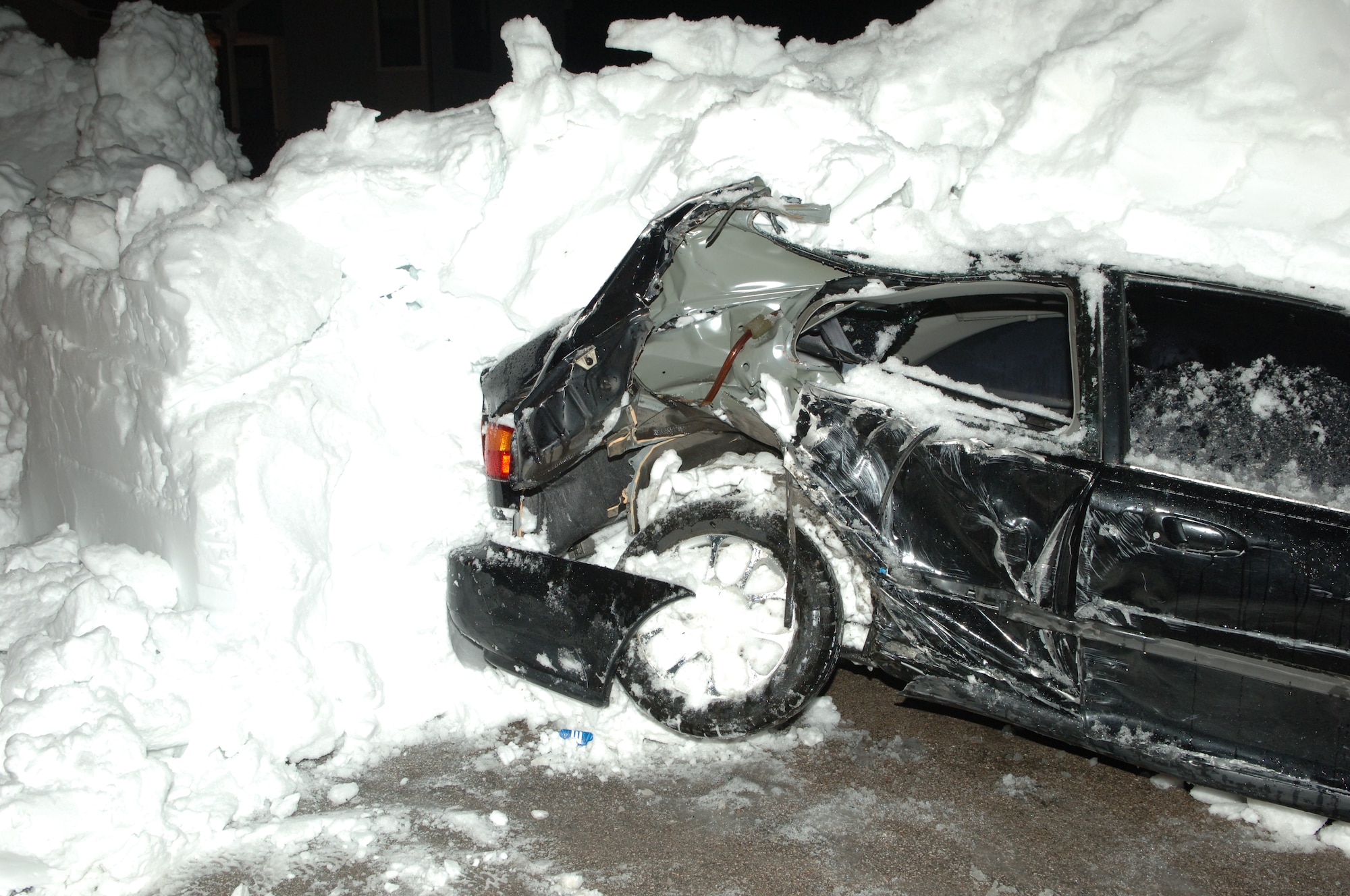 A vehicle sits covered in snow after being hit by a snow plow in base housing, Nov. 15, 2008. The vehicle was hit because it was not removed from the road before the snow fall. (U.S. Air Force photo/Senior Airman Kasey Zickmund)