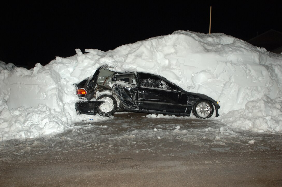 A vehicle sits covered in snow after being hit by a snow plow in base housing here, Nov. 15. The vehicle was hit because it was not removed from the road before the snow fall. (U.S. Air Force photo/Senior Airman Kasey Zickmund)