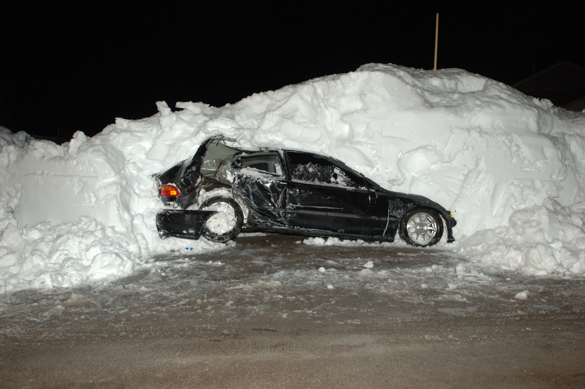 A vehicle sits covered in snow after being hit by a snow plow in base housing here, Nov. 15. The vehicle was hit because it was not removed from the road before the snow fall. (U.S. Air Force photo/Senior Airman Kasey Zickmund)