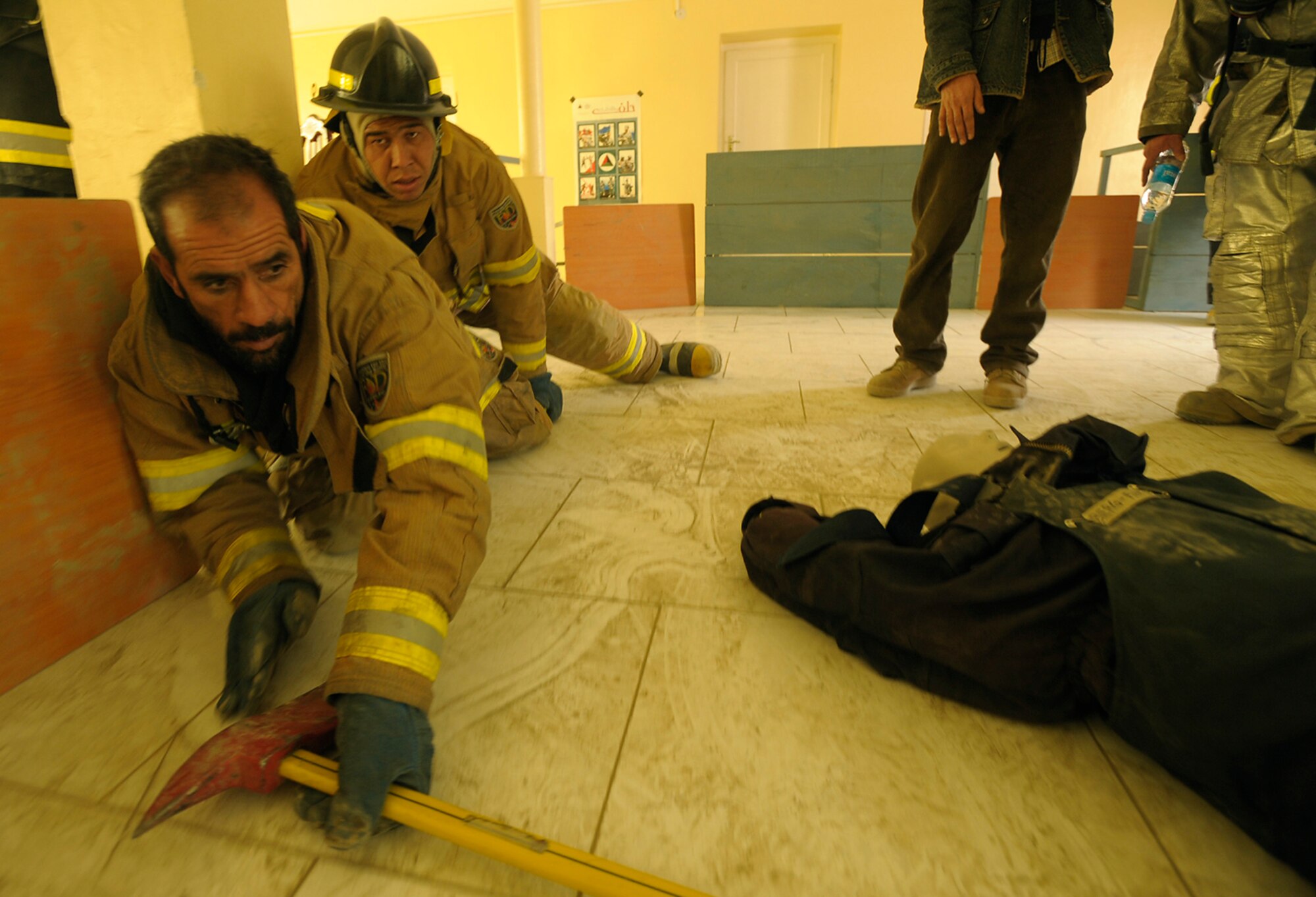 KABUL, Afghanistan -- Two Afghan National Army Air Corps firefighters simulate locating a victim in a smoke filled room during a demonstration at the Joint Fire Academy here. (U.S. Air Force photo/Master Sgt. Keith Brown)