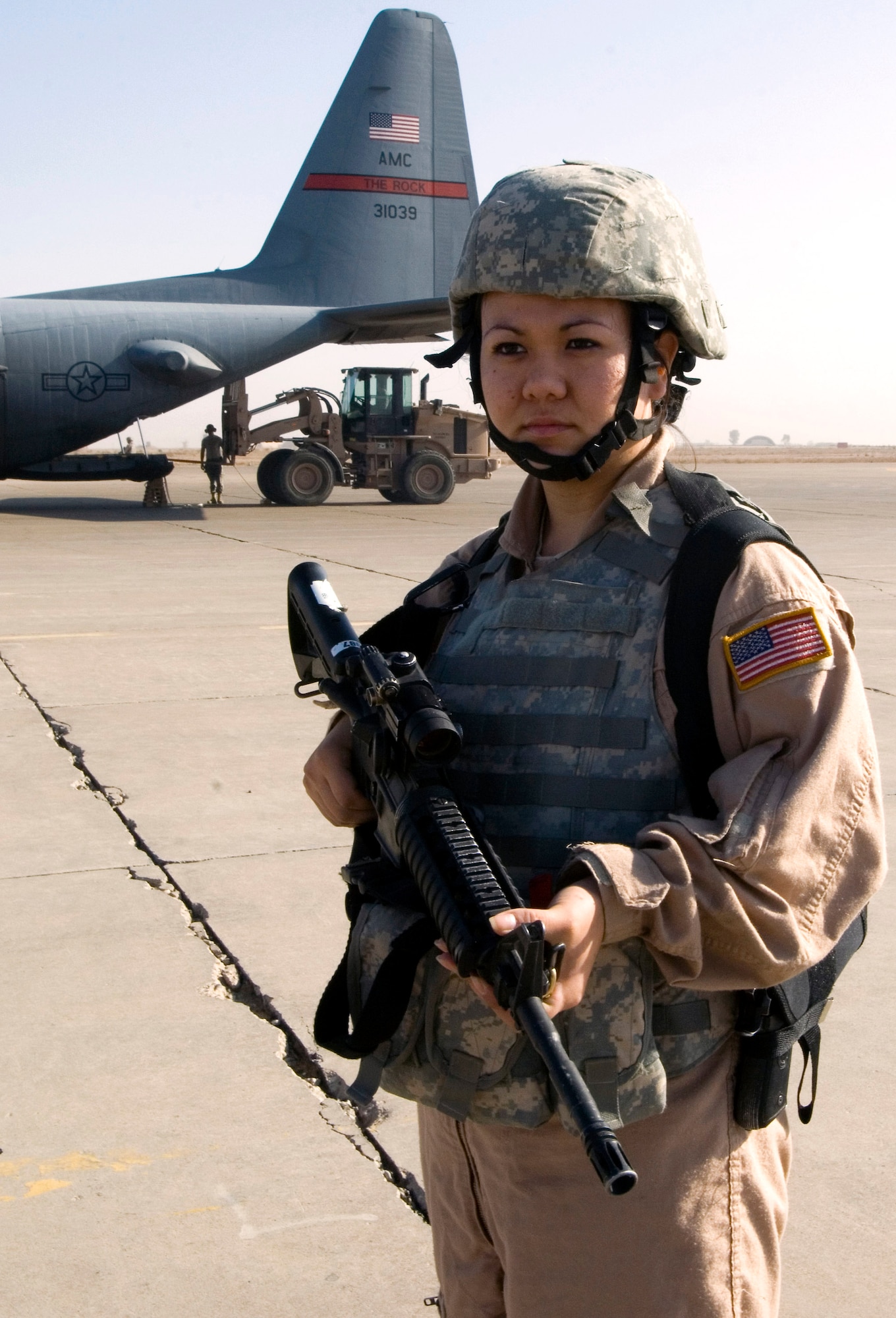 Senior Airman Rosie Munoz scans the area for threats while a 777th Expeditionary Airlift Squadron C-130 Hercules unloads cargo Nov. 22 at a remote location in Iraq. Airman Munoz is a member of a 332nd Expeditionary Security Forces Squadron Fly Away Security Team. She grew up in Seoul, South Korea, and calls El Paso, Texas, home. (U.S. Air Force photo/Tech. Sgt. Erik Gudmundson) 
