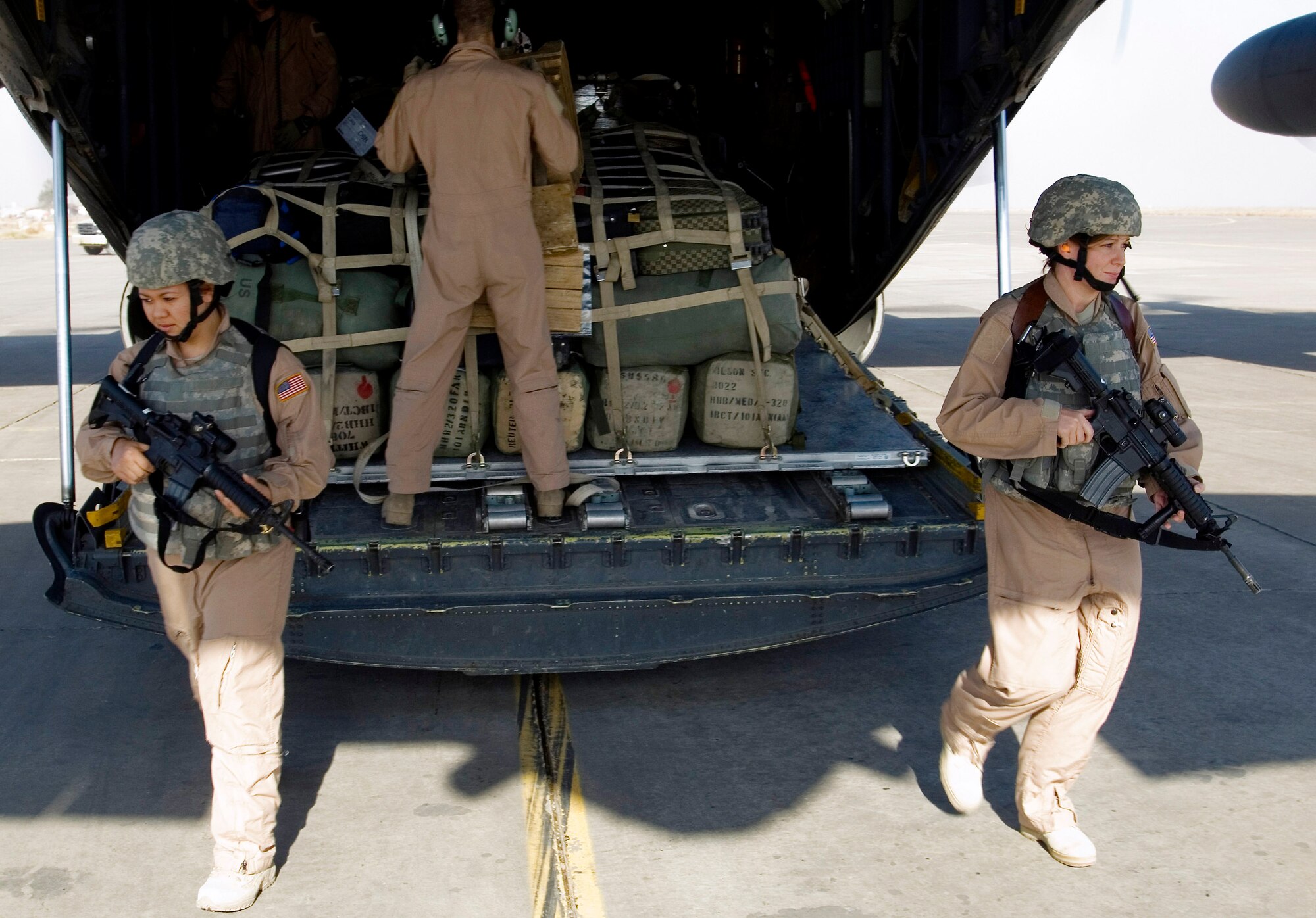 Senior Airmen Rosie Munoz (left) and Michelle Kendall exit to provide ground security for a 777th Expeditionary Airlift Squadron C-130 Hercules Nov. 22 at a remote location in Iraq. Airmen Munoz and Kendall are Fly Away Security Team members with the 332nd Expeditionary Security Forces Squadron. These Airmen make up the only all-female 332nd ESFS FAST, stationed at Joint Base Balad, Iraq. Airman Kendall is a native of Houston, Pa. Airman Munoz calls El Paso, Texas, home. (U.S. Air Force photo/Tech. Sgt. Erik Gudmundson) 
