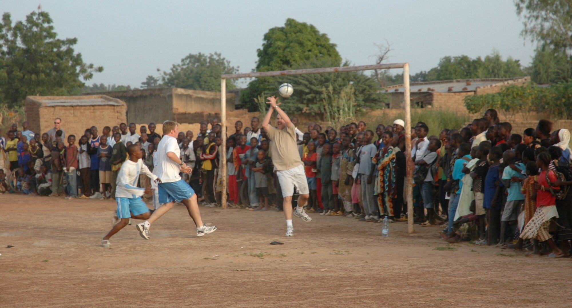 Maj. Mike Holder, 8th Special Operations Squadron, deflects a shot on goal during an Africans vs. Americans soccer match recently in Mali, Africa, while Tech. Sgt. Aaron Brown, 8th SOS, a Malian player, and a crowd of school children look on. The 8th SOS was in Mali supporting FLINTLOCK, a joint/combined training exercise conducted regularly in the Trans-Saharan region designed to build capacity and foster interoperability among African nations. The deployed Airmen hosted the soccer game, as well as a school supply collection, as part of a humanitarian mission in the local community. (U.S. Air Force photo/1st Lt. Lauren Johnson)