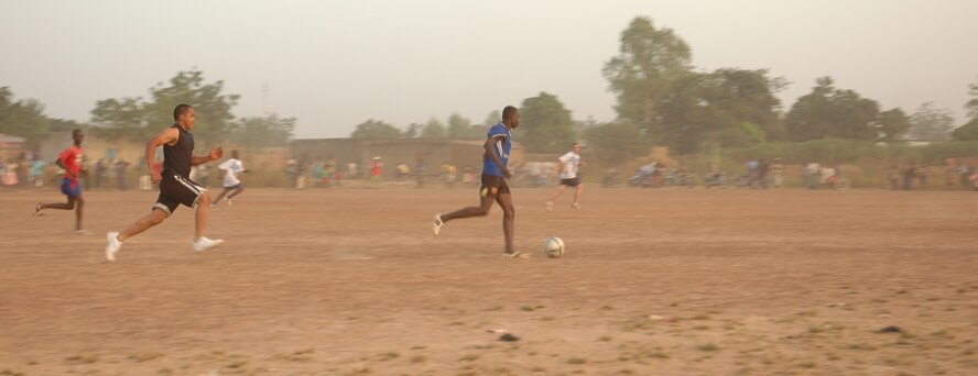 Staff. Sgt. Lawrence Cabusca, 1st Special Operations Squadron Equipment Maintenance Squadron, tries to chase down a Malian player during an Africans vs. Americans soccer game recently in Bamako, Mali. Sergeant Cabusca was in Mali supporting supporting FLINTLOCK, a joint/combined training exercise conducted regularly in the Trans-Saharan region designed to build capacity and foster interoperability among African nations. The soccer game and a corresponding collection of school supplies were part of a humanitarian mission hosted by the deployed Airmen. A crowd of 2,000 watched the Malians win the game 2-0. (U.S. Air Force photo/1st Lt. Lauren Johnson)