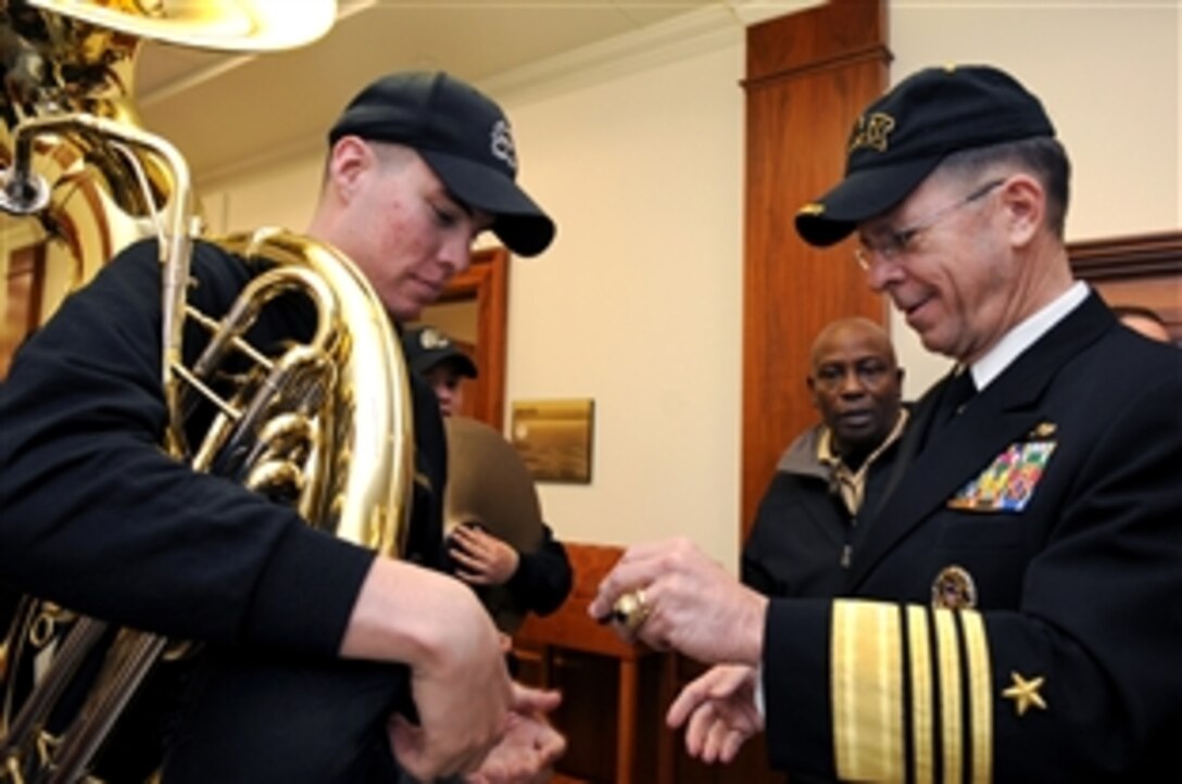 U.S. Navy Adm. Mike Mullen, chairman of the Joint Chiefs of Staff, hands out a coin to a U.S. Military Academy band member outside his office at the Pentagon, Dec. 5, 2008. The band toured the Pentagon to play music before the Army-Navy football game in Philadelphia, Pa., Dec. 6, 2008. 