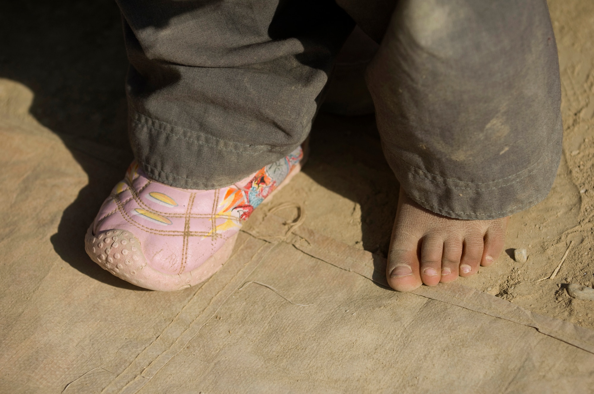 PARWAN REFUGEE CAMP, Afghanistan --An Afghan child tries on donated shoes at a humanitarian assistance visit here. The clothes, shoes, coats and blankets brought to the refugee camp were donations made to Operation Care by American citizens. Donations increased after a 5-year-old boy was treated at the Craig Theater Hospital here who had no shoes. The Doctor caring for him, Lt. Col. Thomas Knolmayer, called home and asked his wife to send a pair of his son's shoes for the child, sparring a rash of shoe donations. Colonel Knolmayer is a general surgeon deployed here from Elmendorf Air Force Base, Alaska. (U.S. Air Force photo/Master Sgt. Keith Brown)