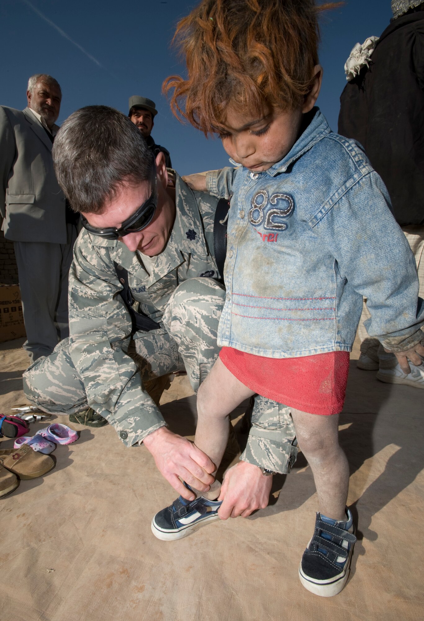 PARWAN REFUGEE CAMP, Afghanistan -- Lt. Col. (Dr.) Thomas Knolmayer helps a Afghan girl try on donated shoes at a humanitarian assistance visit here. The clothes, shoes, coats and blankets brought to the refugee camp were donations made to Operation Care by American citizens. Donations increased after a 5-year-old Afghan boy arrived at the Craig Theater Hospital with out shoes. Colonel Knolmayer asked his wife to send a pair of their son's shoes for the boy. That started a shoe and clothing drive for people at the refugee camp and other communities in Afghanistan. Colonel Knolmayer is a general surgeon deployed here from Elmendorf Air Force Base, Alaska. (U.S. Air Force photo/Master Sgt. Keith Brown)
