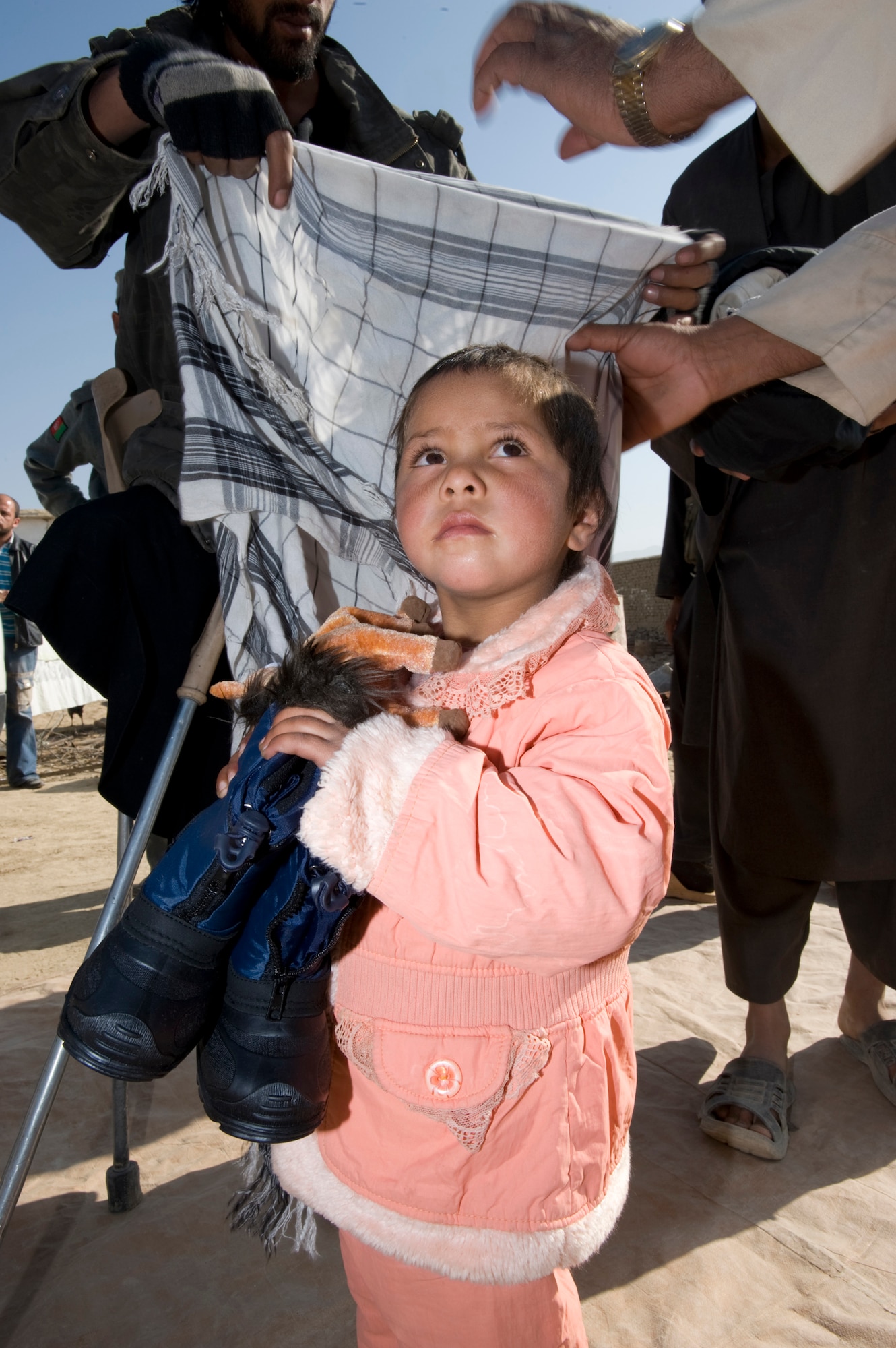PARWAN REFUGEE CAMP, Afghanistan -- An Afghan girl tries on clothes and shoes during a humanitarian assistance visit to distribute items donated to Operation Care by American citizens. stance visit. The items distribute were donated to Operation Care by American citizens. Donations increased after a 5-year-old boy was treated at the Craig Theater Hospital here who had no shoes. The doctor caring for him, Lt. Col. Thomas Knolmayer, called home and asked his wife to send a pair of his son's shoes for the child, sparring a rash of shoe donations. Colonel Knolmayer is a general surgeon deployed here from Elmendorf Air Force Base, Alaska. (U.S. Air Force photo/Master Sgt. Keith Brown)
