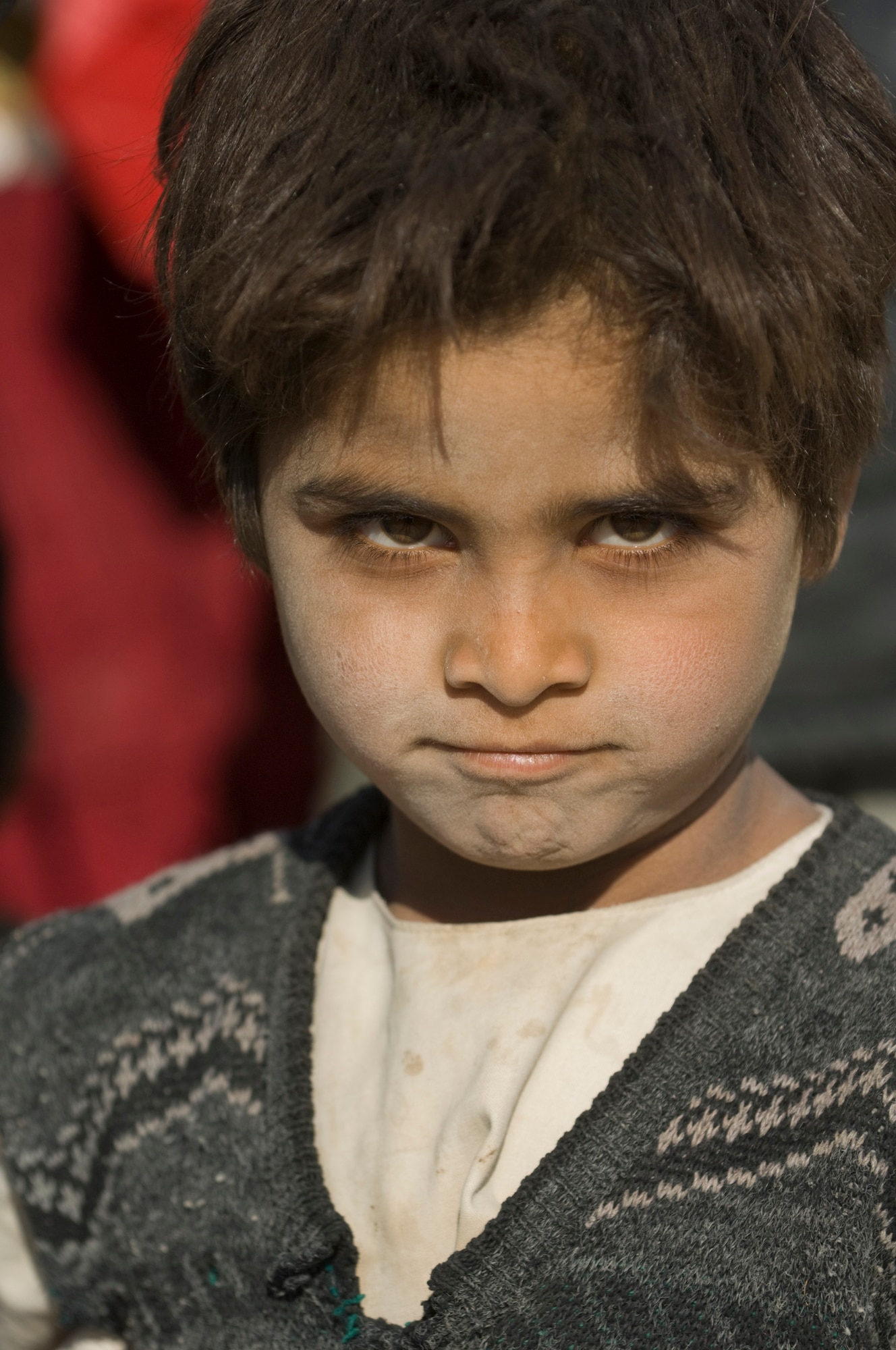 PARWAN REFUGEE CAMP, Afghanistan -- An Afghan boy waits to receive shoes and clothes during a humanitarian assistance visit. The items distribute were donated to Operation Care by American citizens. Donations increased after a 5-year-old boy was treated at the Craig Theater Hospital here who had no shoes. The doctor caring for him, Lt. Col. Thomas Knolmayer, called home and asked his wife to send a pair of his son's shoes for the child, sparring a rash of shoe donations. Colonel Knolmayer is a general surgeon deployed here from Elmendorf Air Force Base, Alaska. (U.S. Air Force photo/Master Sgt. Keith Brown)