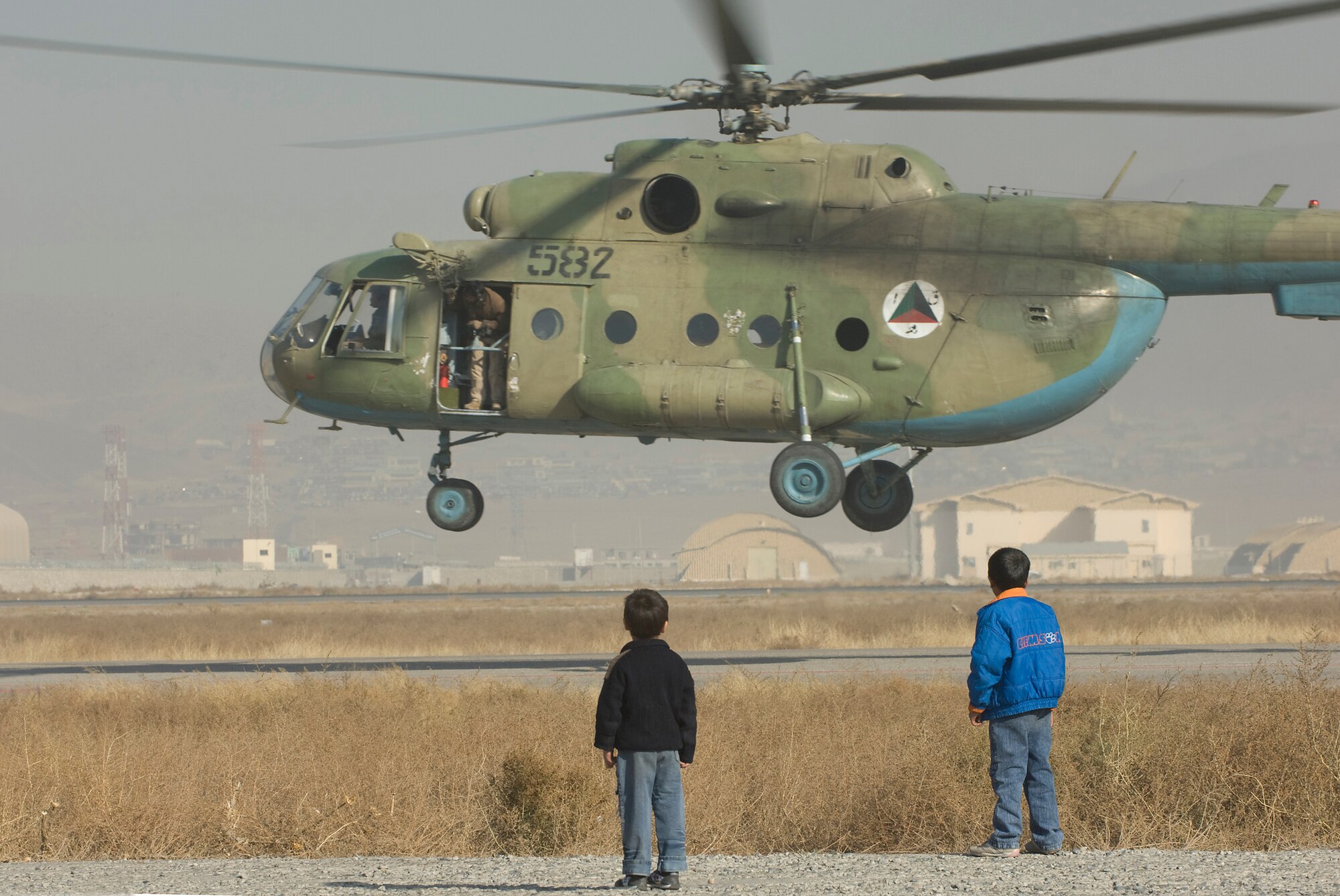 KABUL, Afghanistan -- Two Afghan boys watch as an Afghan National Army Air Corps Mi-17 takes off here. The ANAAC is mentored by the 438th Air Expeditionary Wing. U.S. Air Force helicopter pilots regularly fly with the Afghan crews as instructor pilots on the Soviet made aircraft. (U.S. Air Force photo/Master Sgt. Keith Brown)