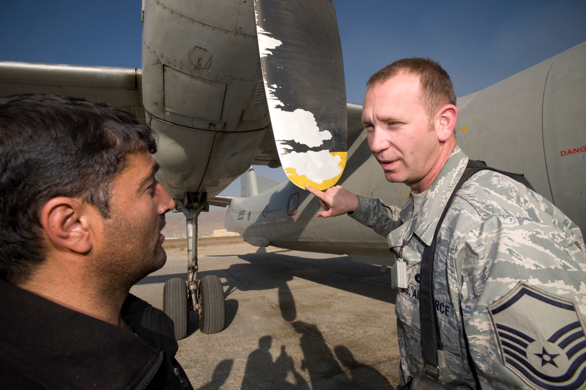 KABUL, Afghanistan -- Master Sgt Chris Lipphardt gets a lesson in Dari, one of the two main languages used in Afghanistan. Learning how to say 'yellow' as in the color of the end of this propeller, in the local language has been a tremendous asset in mentoring the ANAAC on flying operations. Sergeant Lipphardt is the fixed-wing maintenance mentor and superintendent. (U.S. Air Force photo/Master Sgt. Keith Brown)